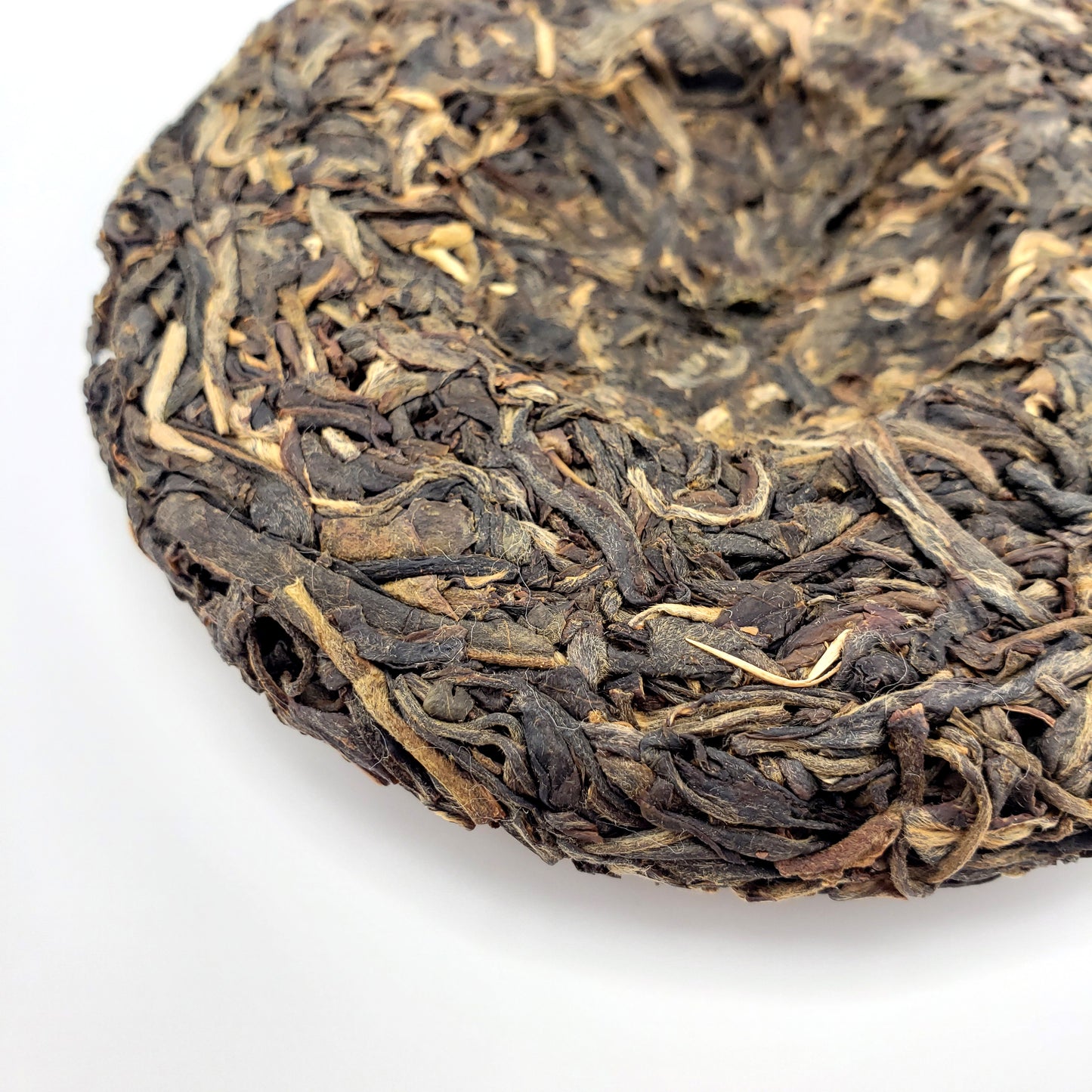 Close-up of a compressed tea cake with intricate leaf patterns on a white background