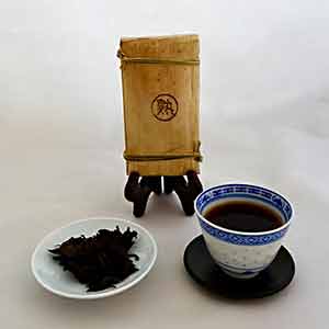 Tea brick, loose tea leaves, and a cup of tea on a white background