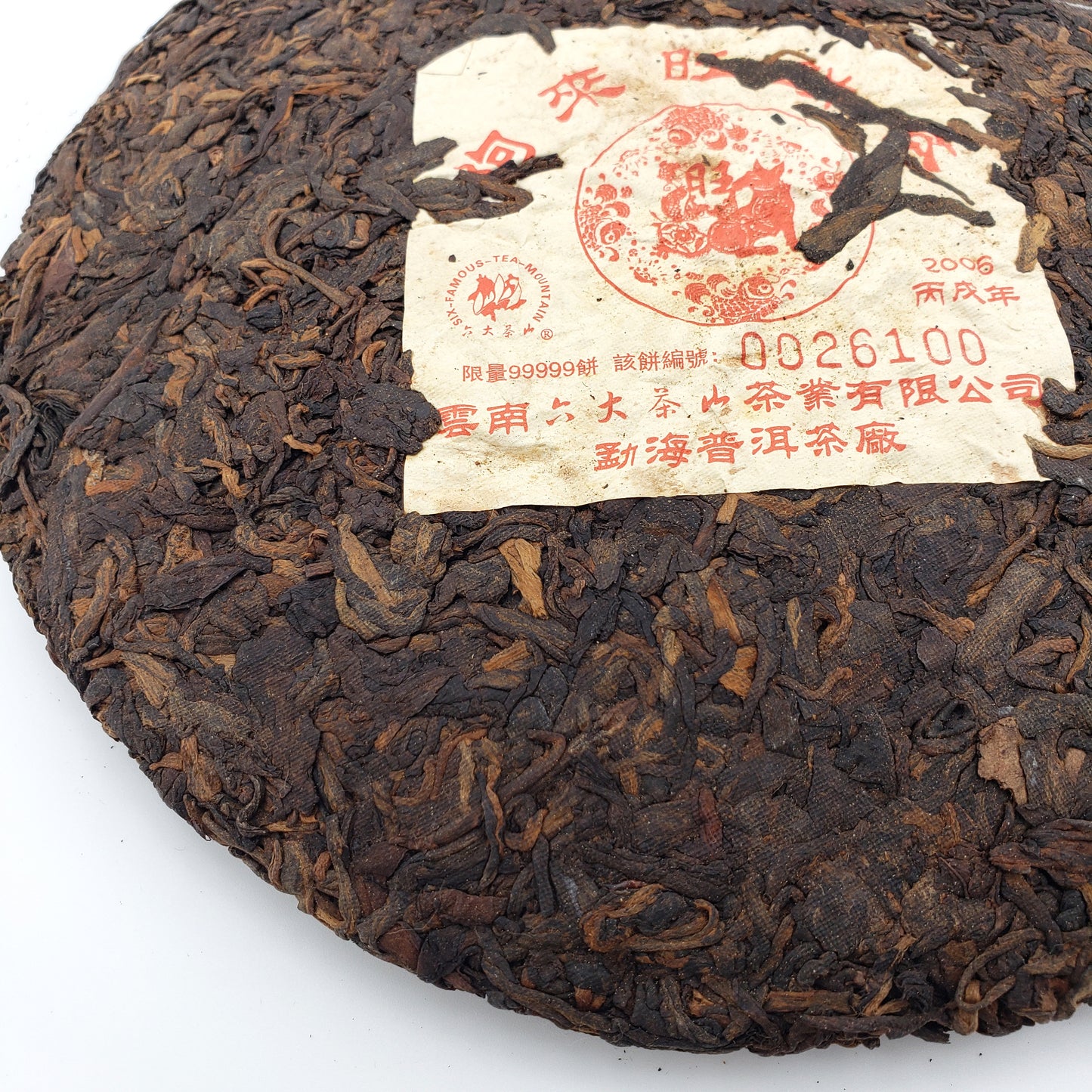 Round dark brown tea cake with a label on a white background