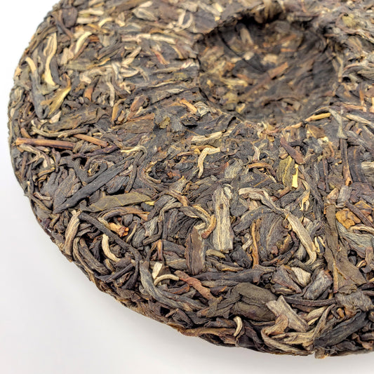 Close-up of raw Pu-erh tea leaves pressed into a cake on a white background