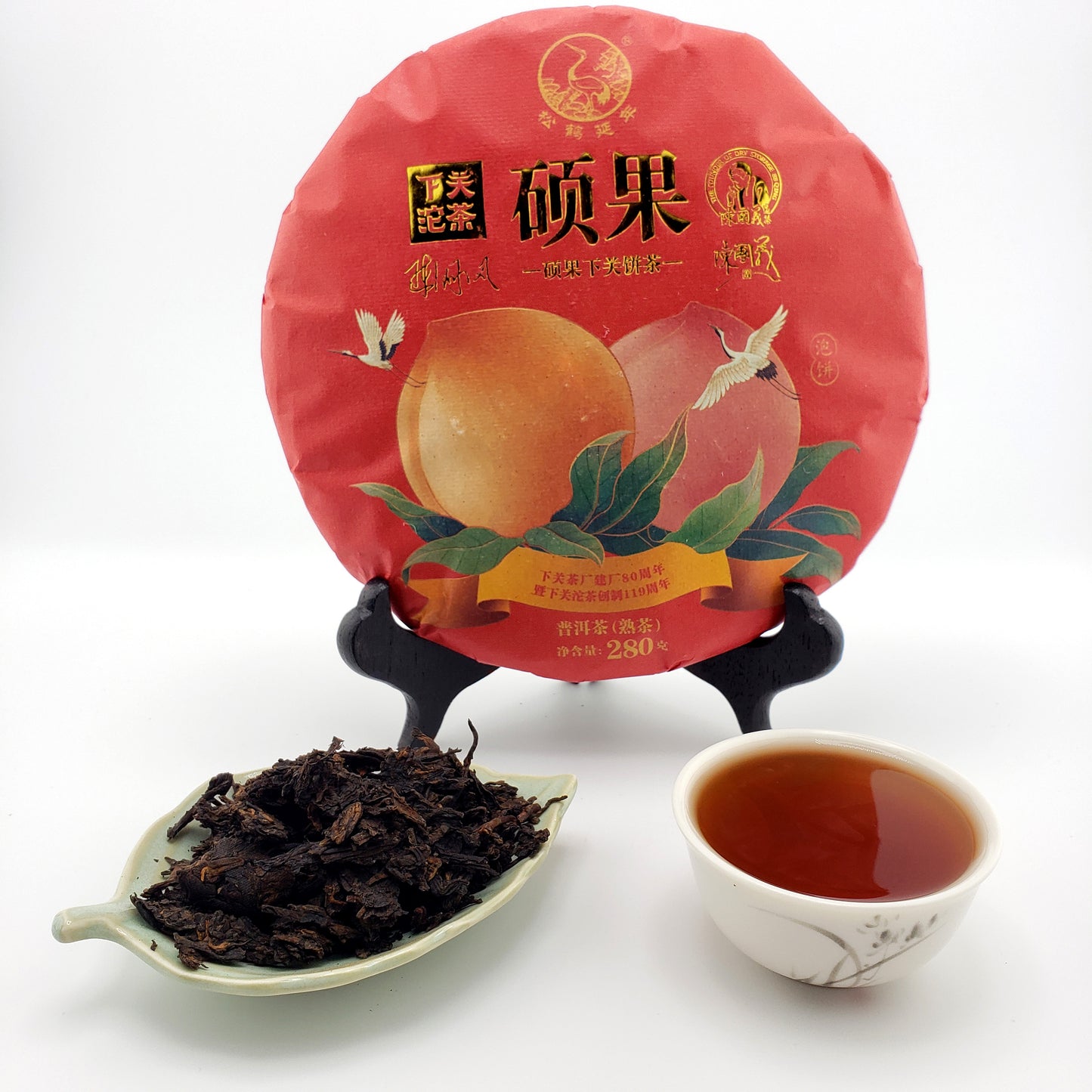 Red tea cake with peach illustration, cup of tea, and tea leaves on a white background