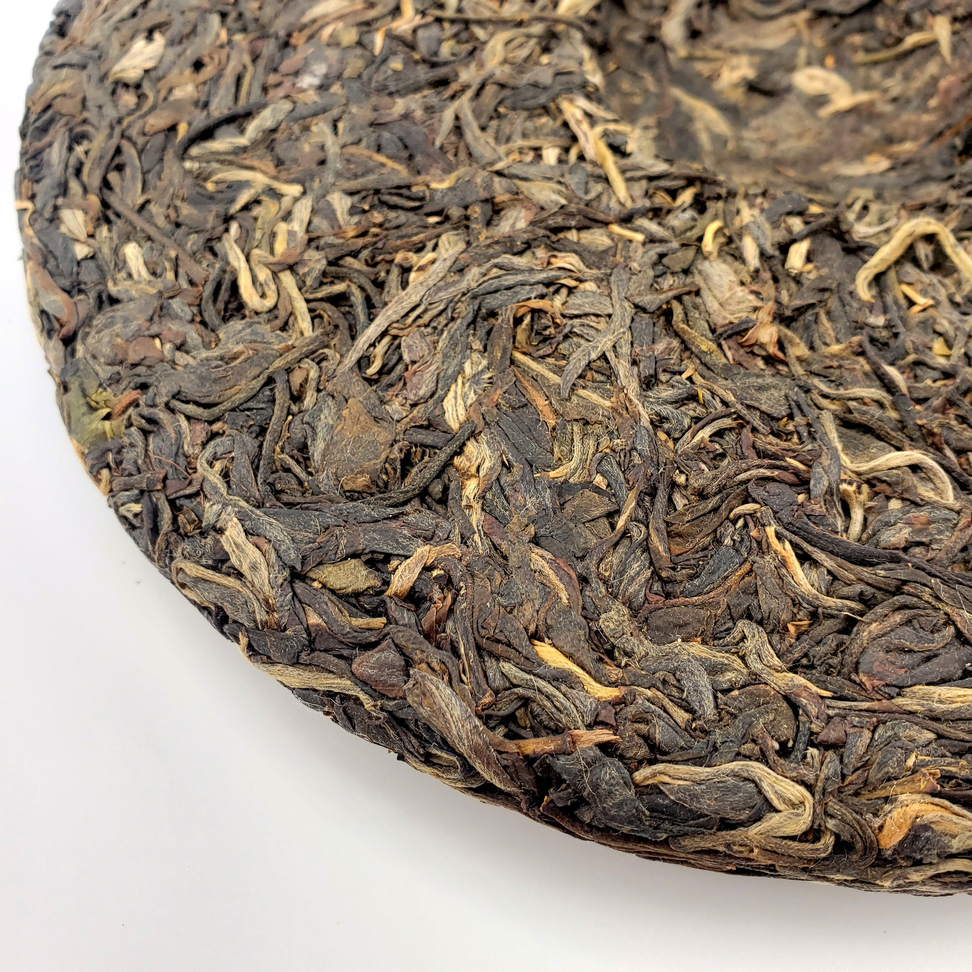 Close-up of a round cake of Pu-erh tea leaves on a white background