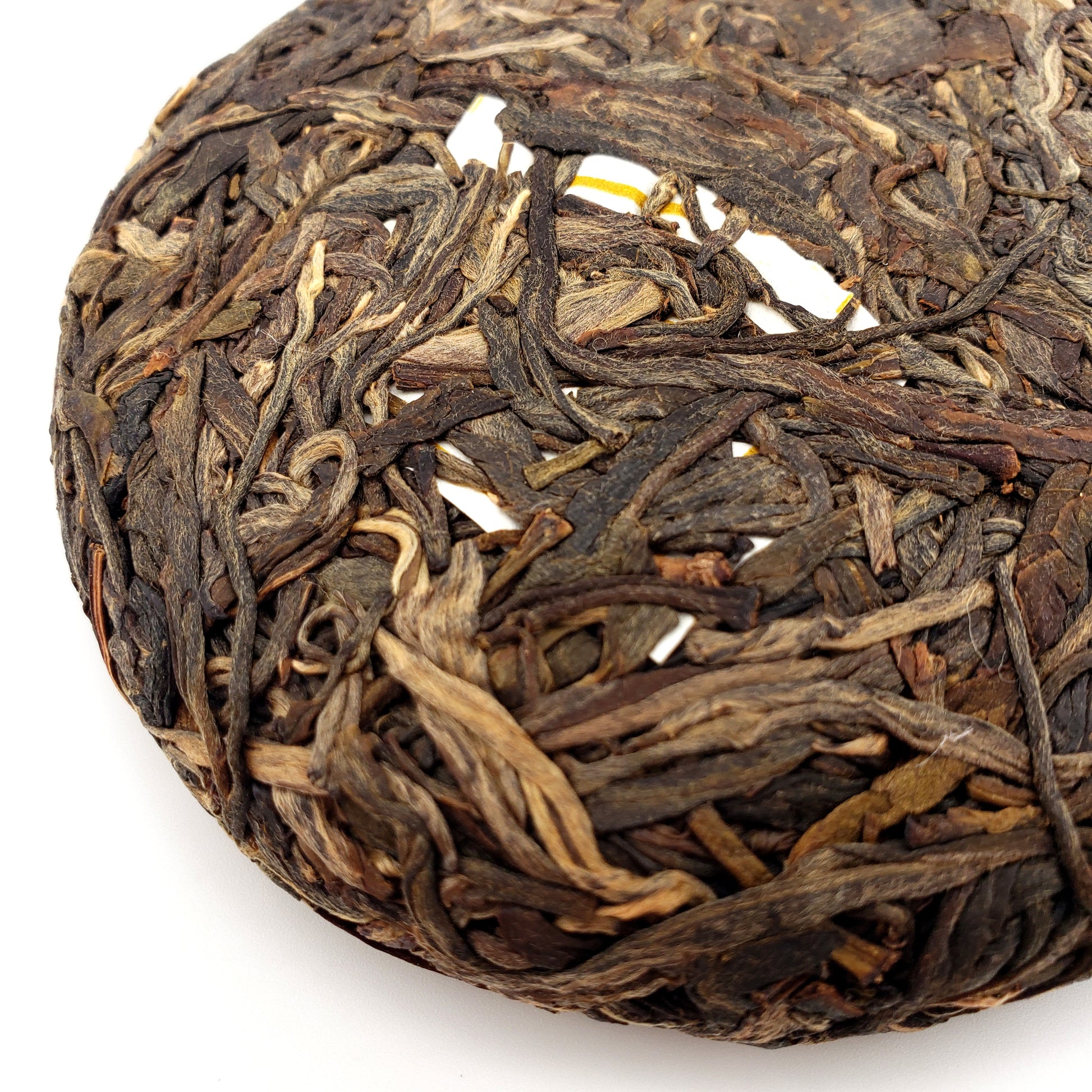 Close-up of a cake of compressed tea leaves on a white background
