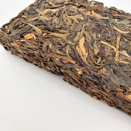 A block of aged tea with dark brown and beige colors on a white background