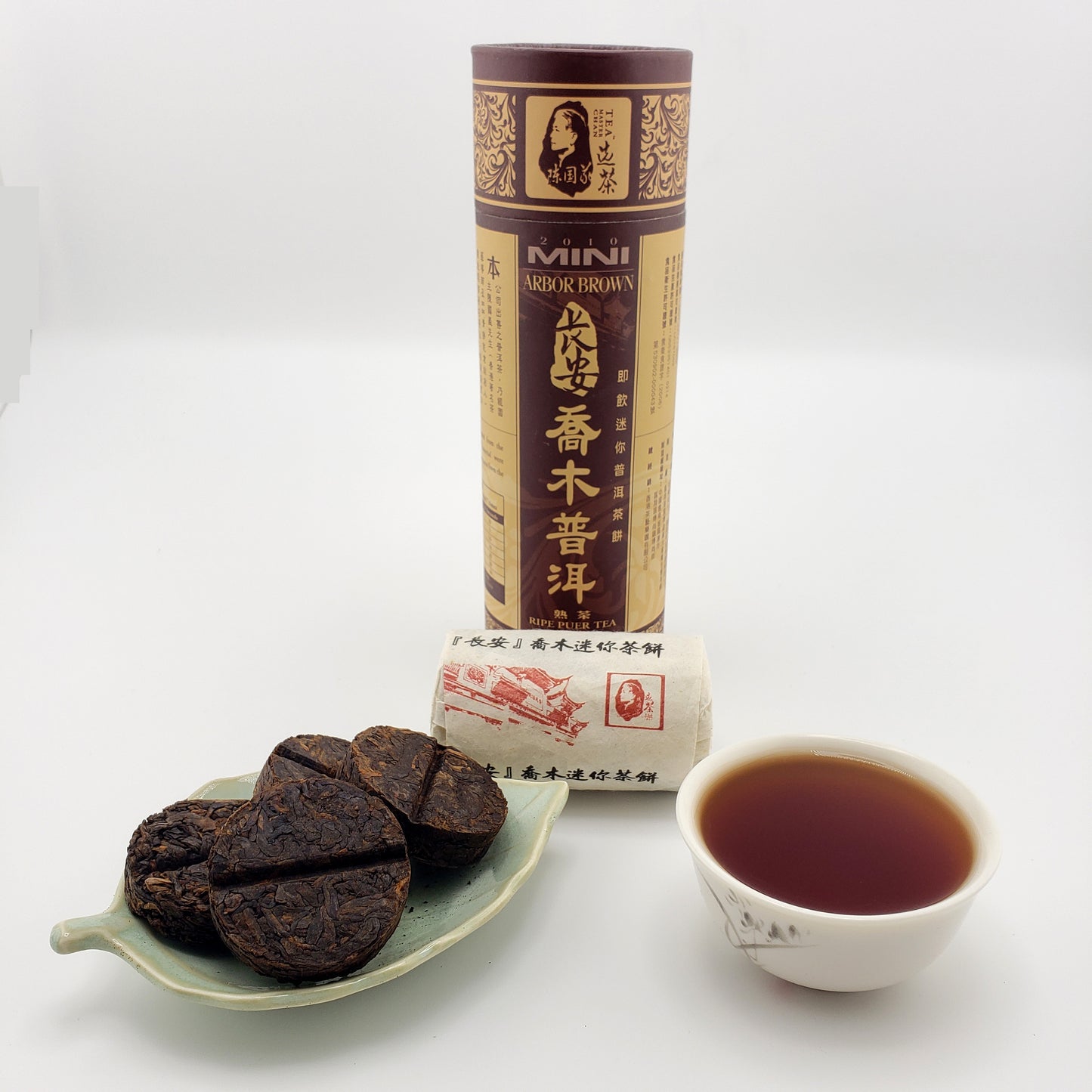 Puer tea coins, packaging, and a cup of tea on a white background
