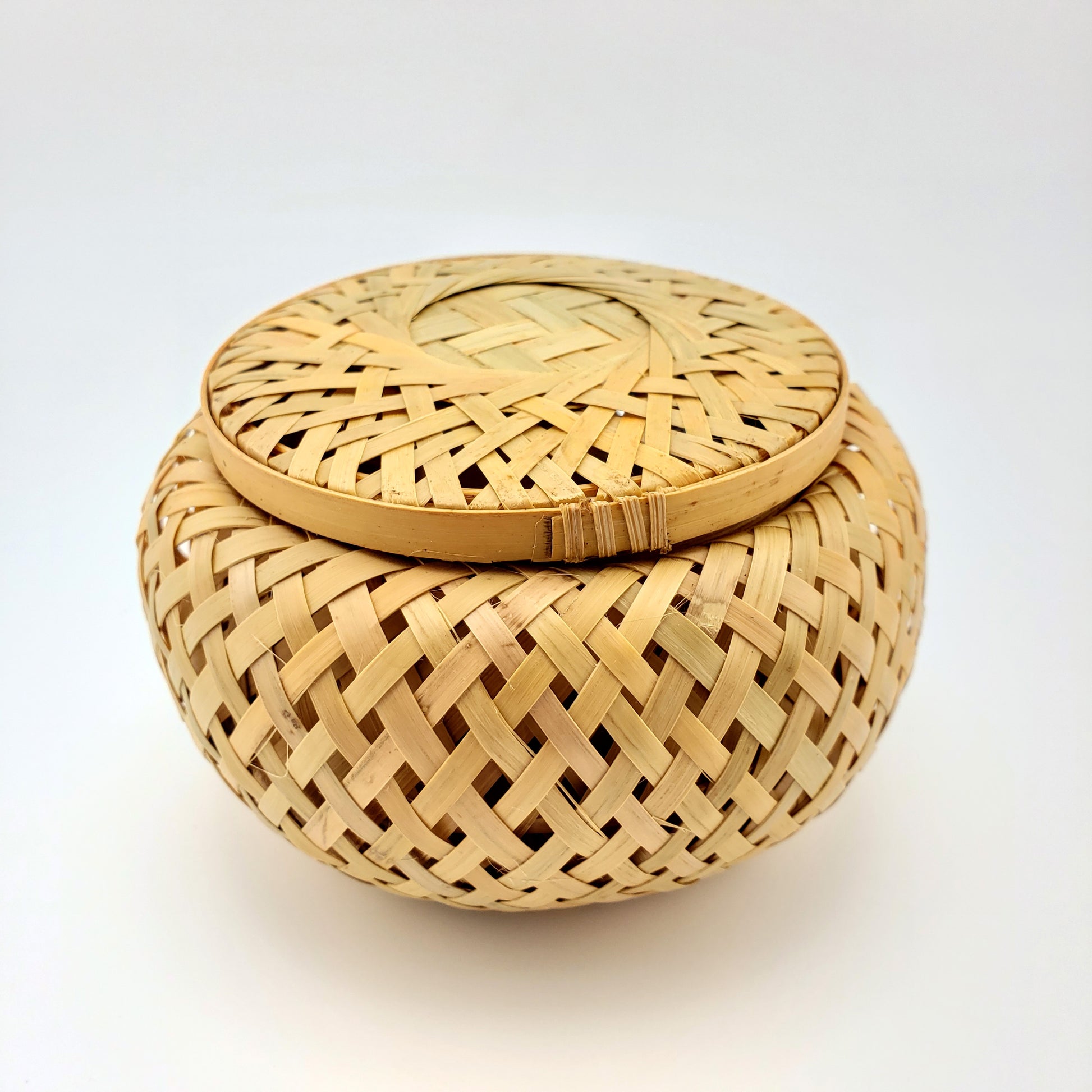 Woven bamboo basket with lid on a white background