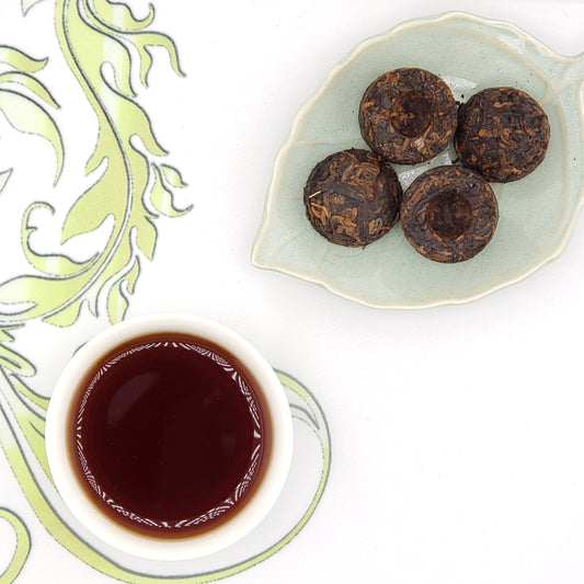 Tea balls on a plate with a cup of tea on a decorative mat