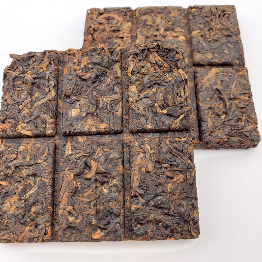 Square pieces of dark brown tea on a white background