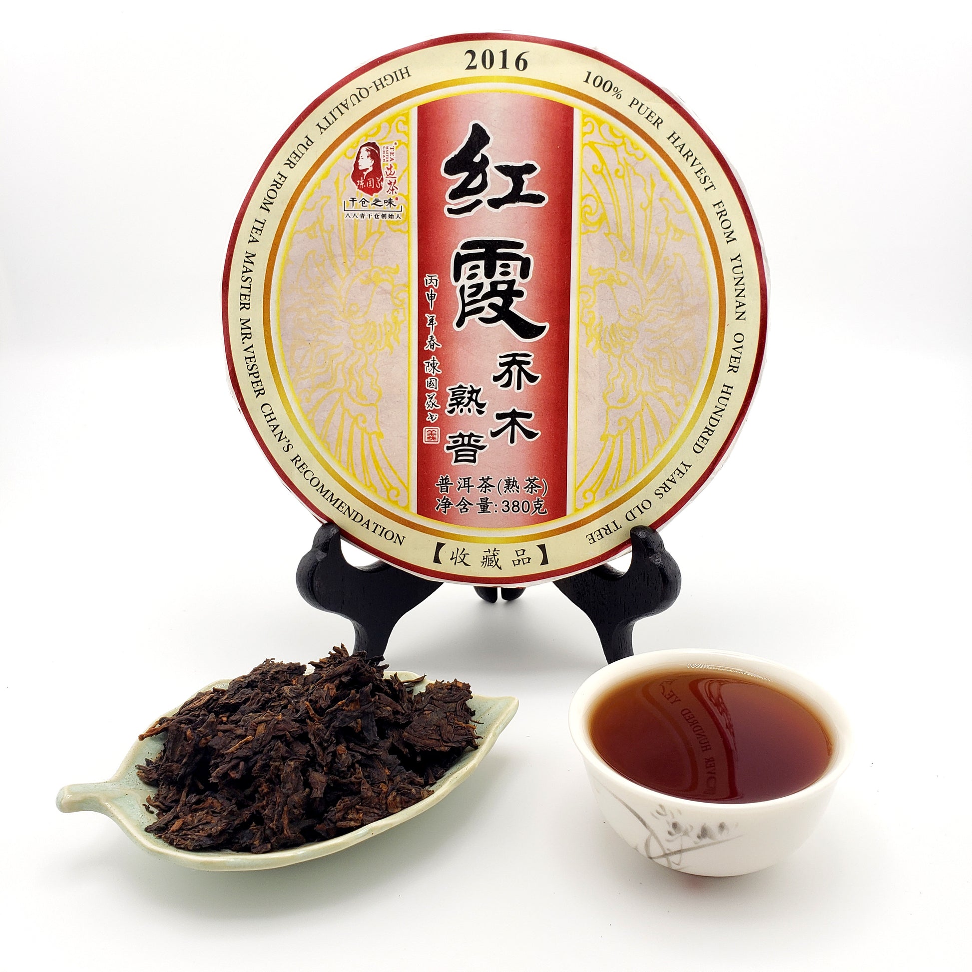 Pu-erh tea cake with a cup of tea and a scoop of tea leaves on a white background