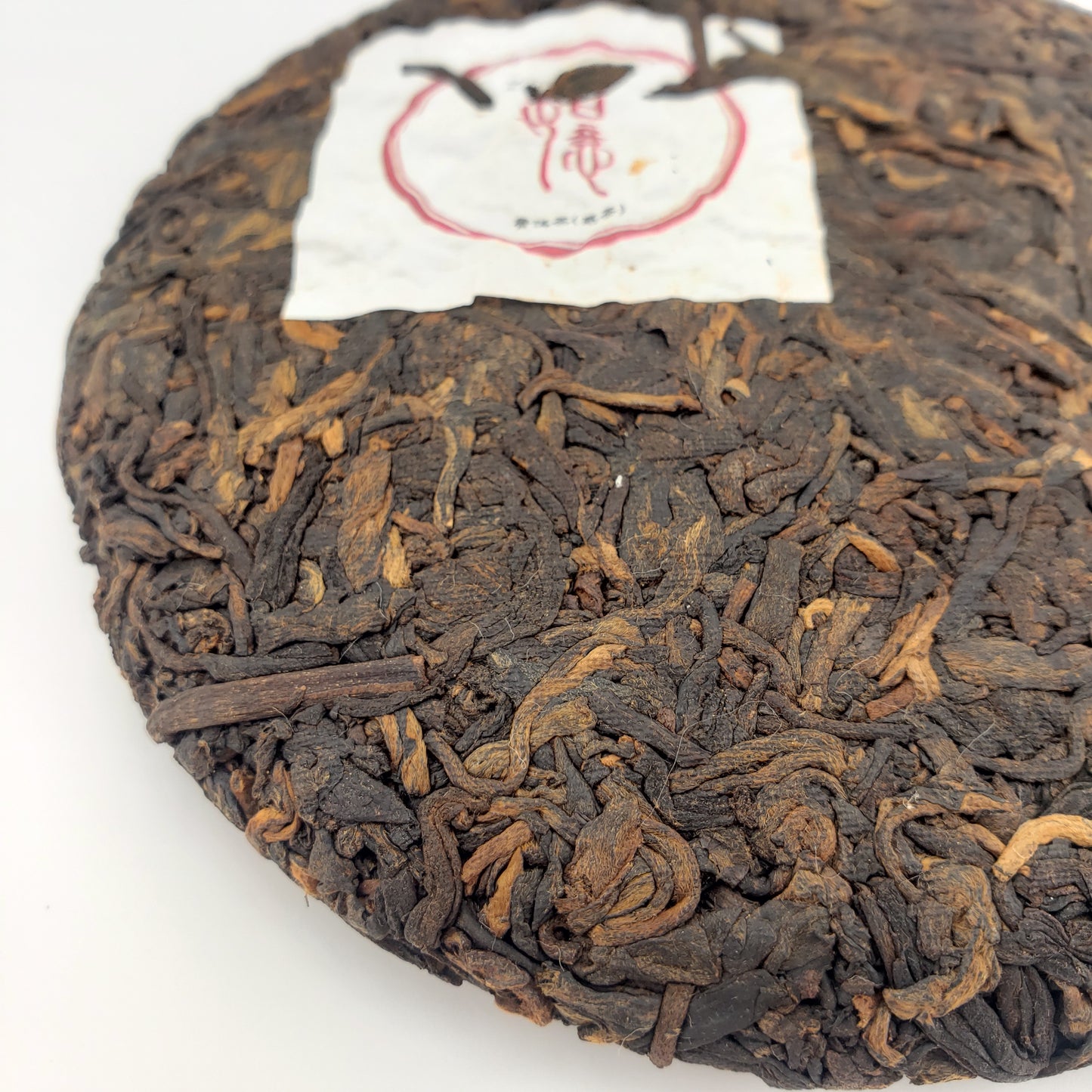 Close-up of a pressed tea cake with a white label on a white background