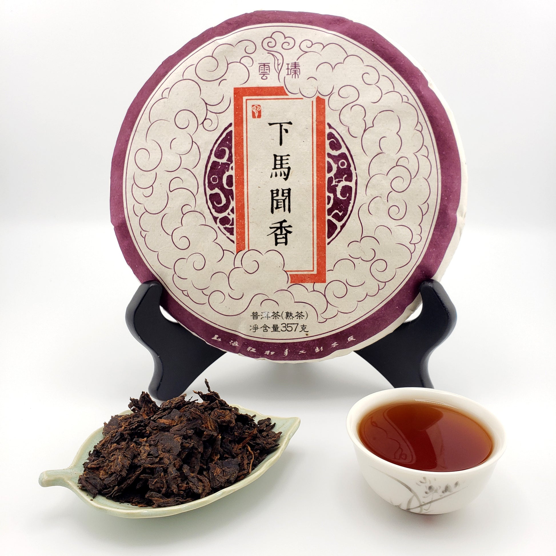 Puer tea cake with a cup of tea and tea leaves on a white background